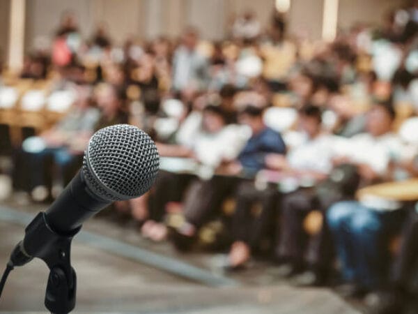 Microphone over the Abstract blurred photo of conference hall or seminar room with attendee background